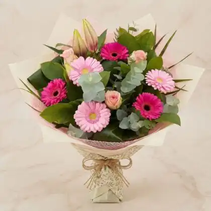 Vibrant hot pink gerbera bouquet featuring fresh lilies in a professional hand-tied floral arrangement.