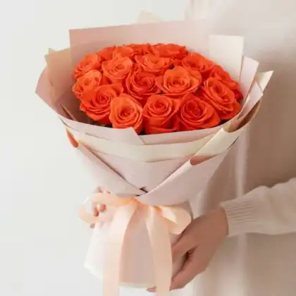 Hand-tied orange rose bridal bouquet wrapped in premium paper with a soft peach ribbon for wedding ceremonies.