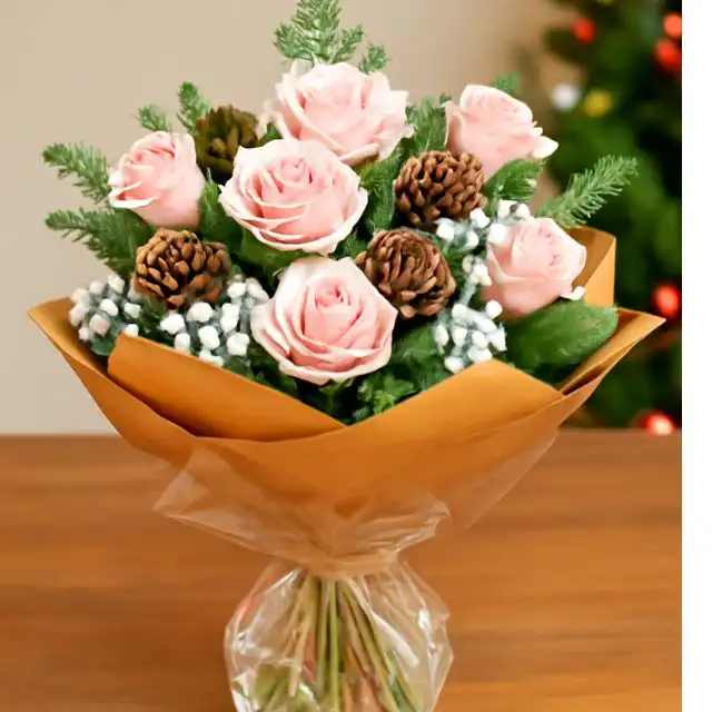 Luxury Frost Pink Christmas Bouquet 1 Hand-tied pink Christmas bouquet with fresh pink roses, snowy accents, natural pine cones, and pine foliage, wrapped in a brown paper cone.